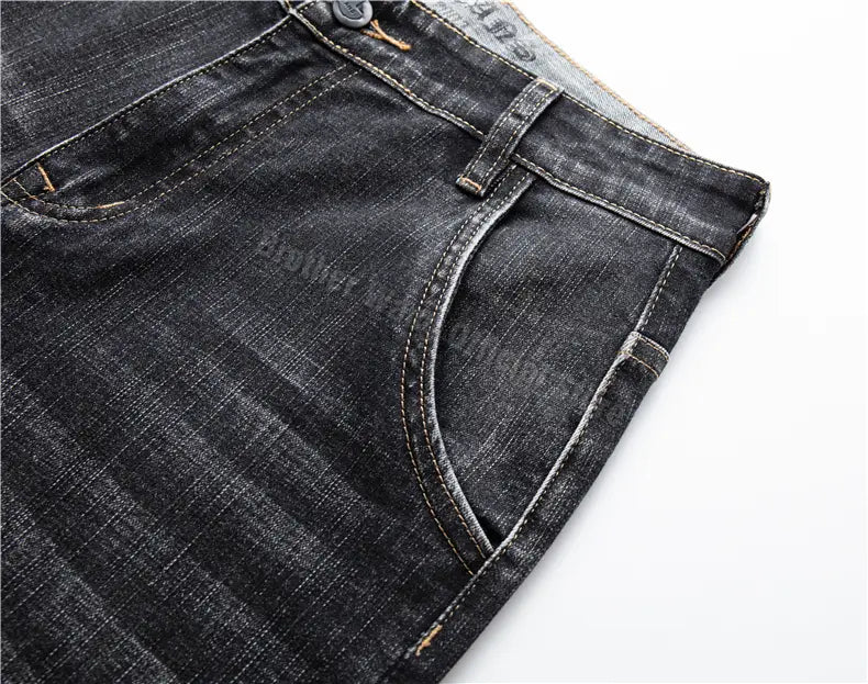 Jeans en denim stretch pour hommes, coupe regular fit, en denim foncé, avec une texture légèrement usée classique et des détails de couture visibles.