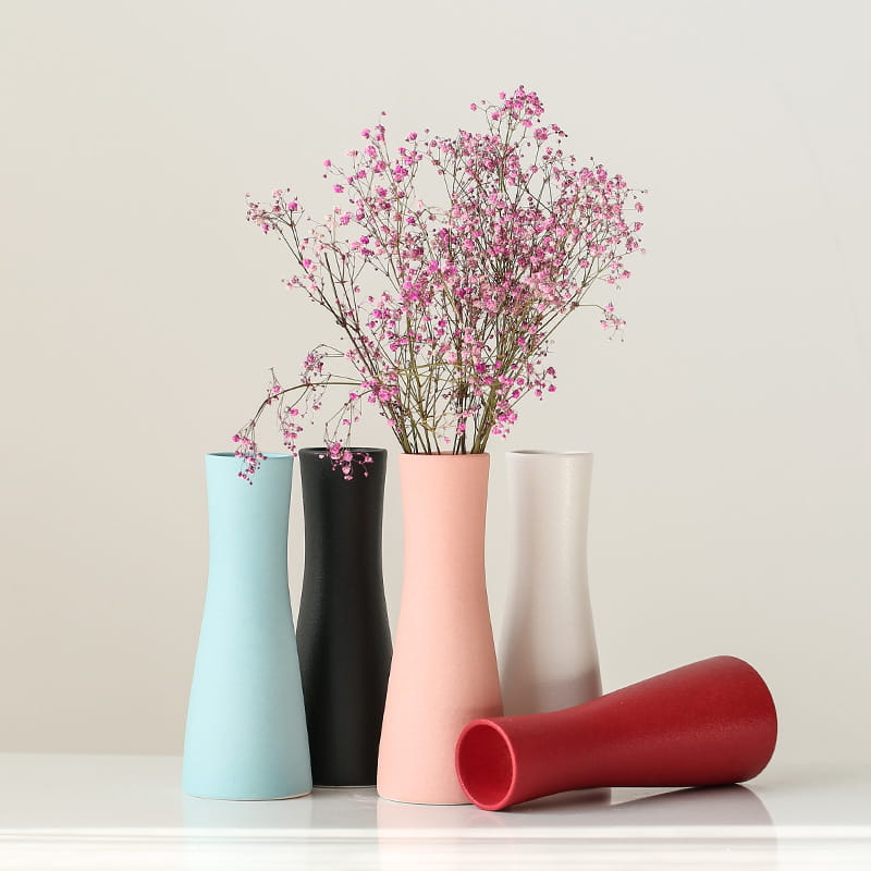 A sleek modern white ceramic vase in soft pink with a smooth matte finish and tapered silhouette ideal for floral decor.