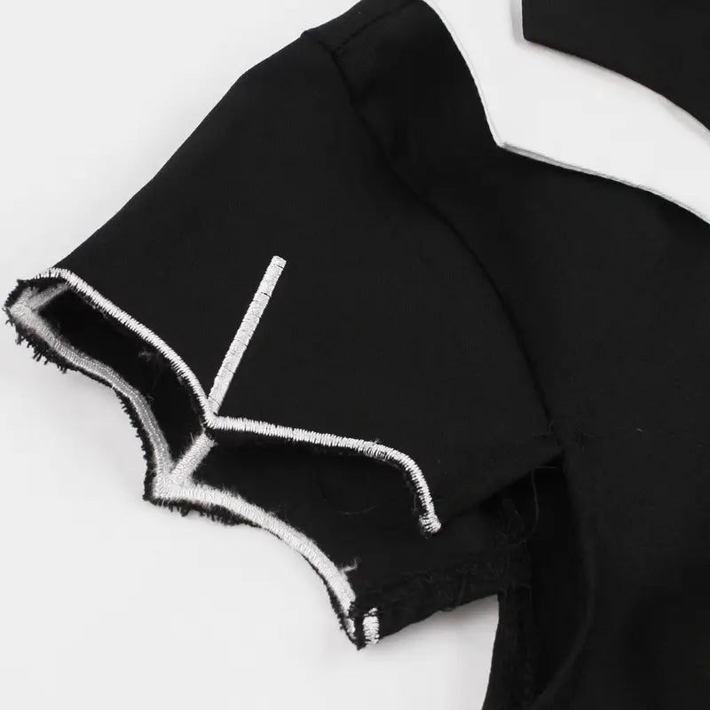 schwarzes kurzärmeliges Oberteil mit ausgefransten Kanten und weißer Ziernaht entlang des Ärmelabschlusses, kombiniert mit einem Vintage-Bat-Embroiderie-A-Linien-Kleid.