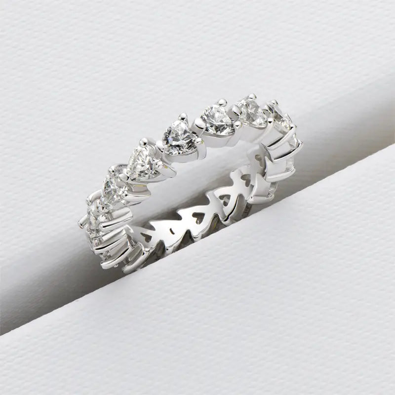 Une élégante bague d’éternité cœur en argent sterling, dotée d’une rangée continue de diamants étincelants taillés en forme de cœur et en triangles.