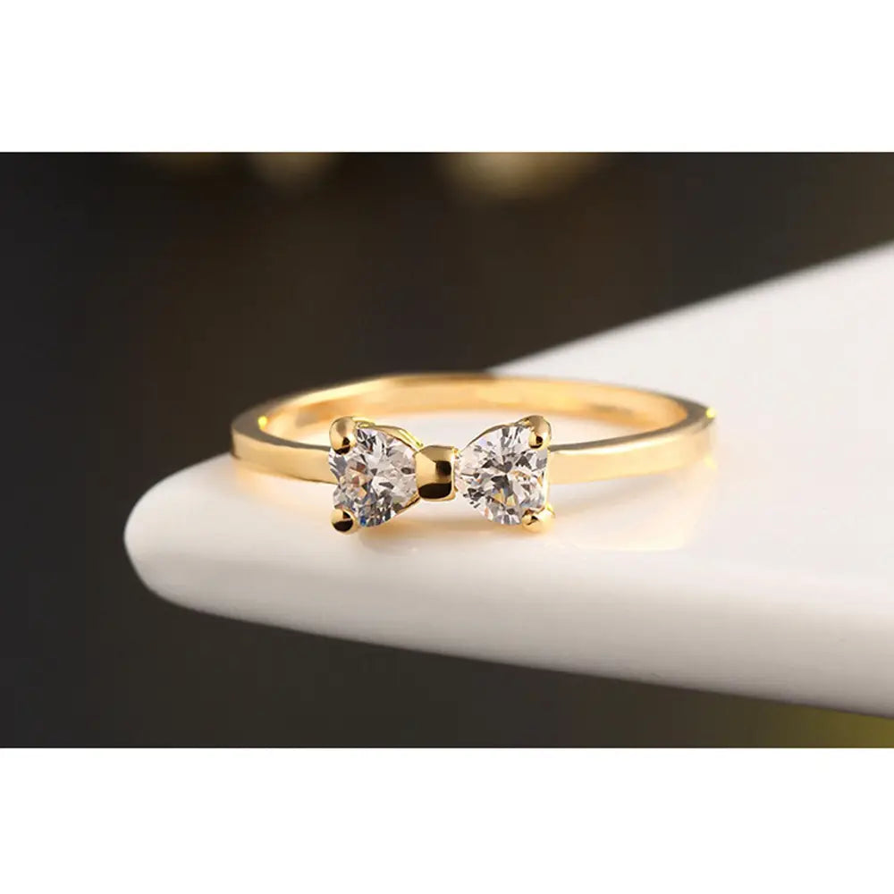 Bague de mariage en argent sterling avec nœud de forme dorée, présentant deux pierres précieuses en oxyde de zirconium cubique claires et facettées.