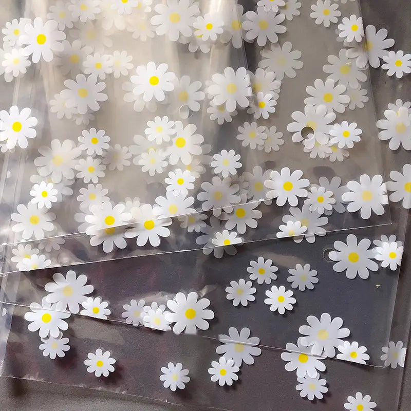 Blumige, durchsichtige Reisekosmetiktasche aus durchsichtigem Kunststoff, verziert mit weißen Gänseblümchen mit gelben Zentren.