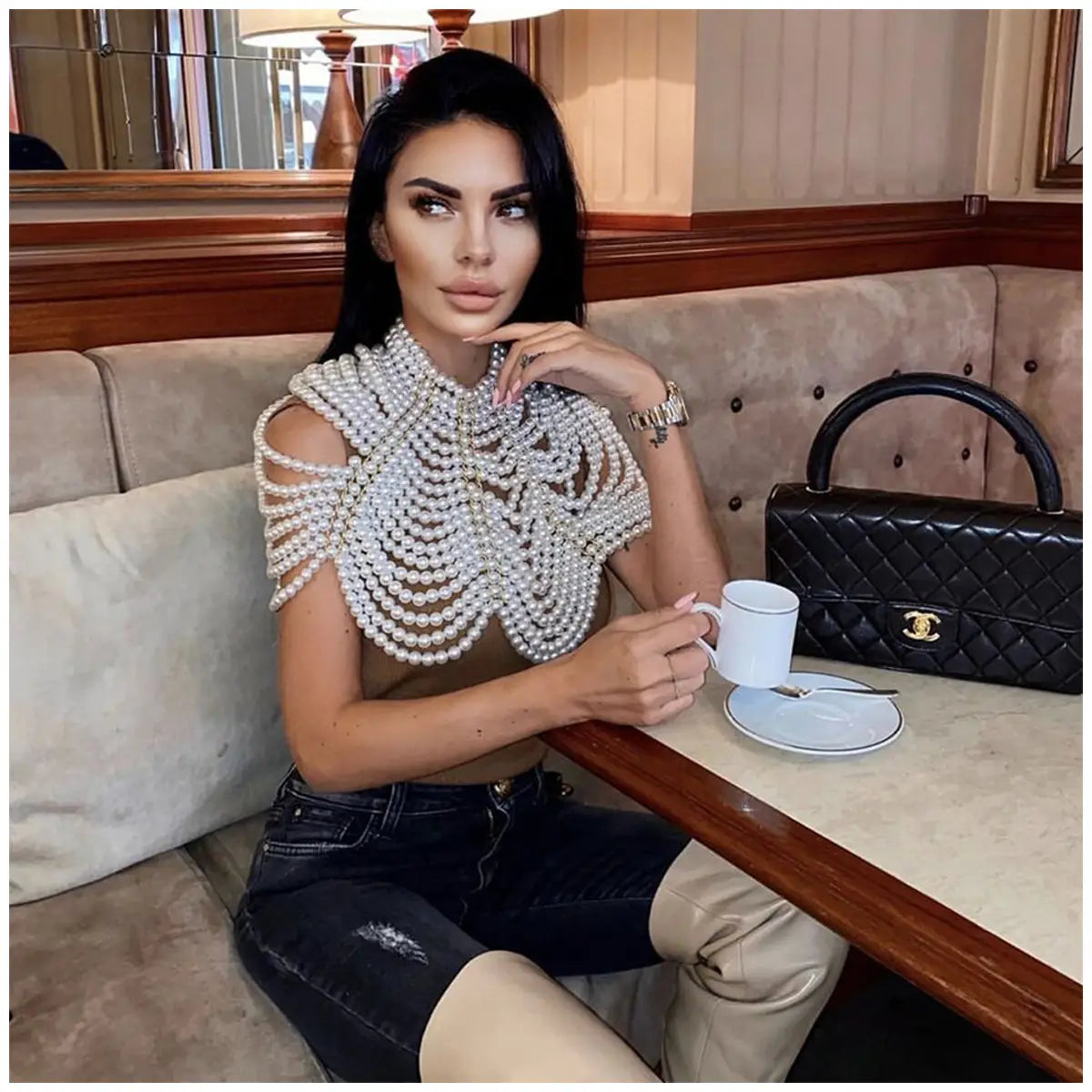 Une femme porte un collier de mode en chaîne corporelle de perles, présentant plusieurs rangées de perles blanches dans un design délicat à superpositions en forme de décolleté épaules-nues.