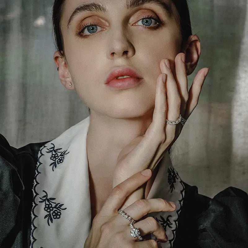 Une femme portant un chemisier brodé noir et blanc à manches bouffantes, modélisant une bague d’éternité cœur en argent sterling.