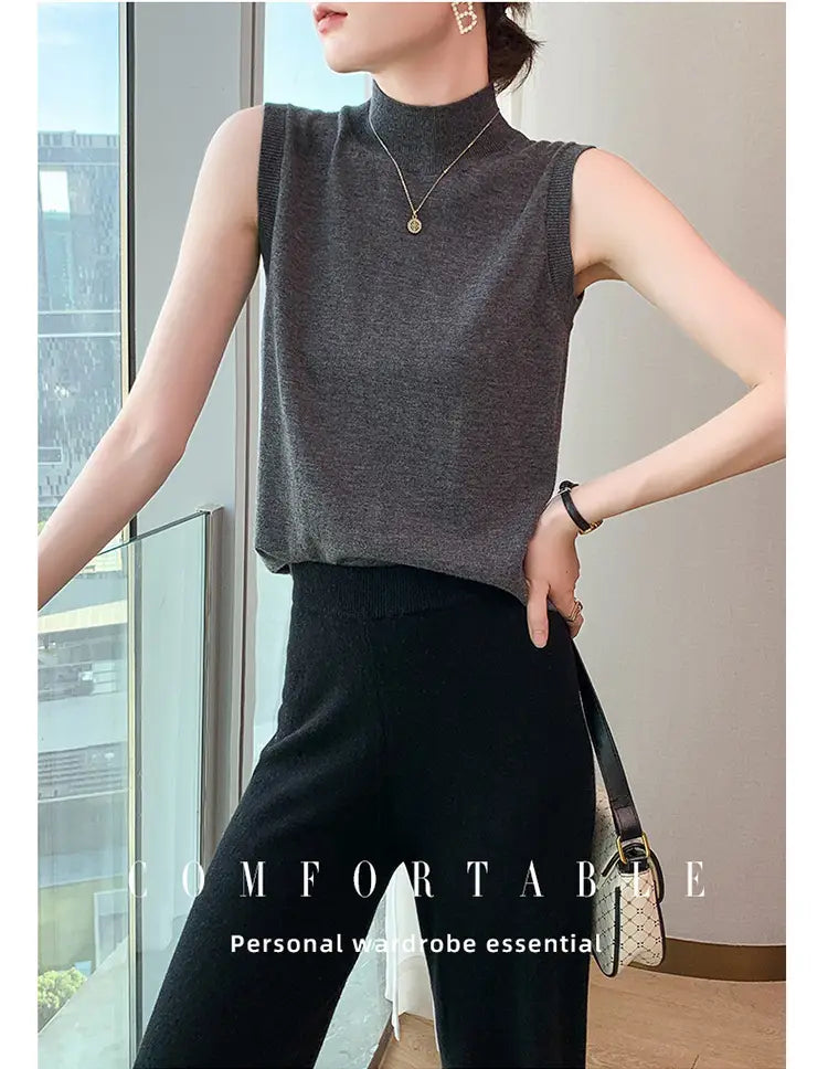 A sleek dark gray wool turtleneck sleeveless sweater vest with a ribbed knit texture and high neckline.