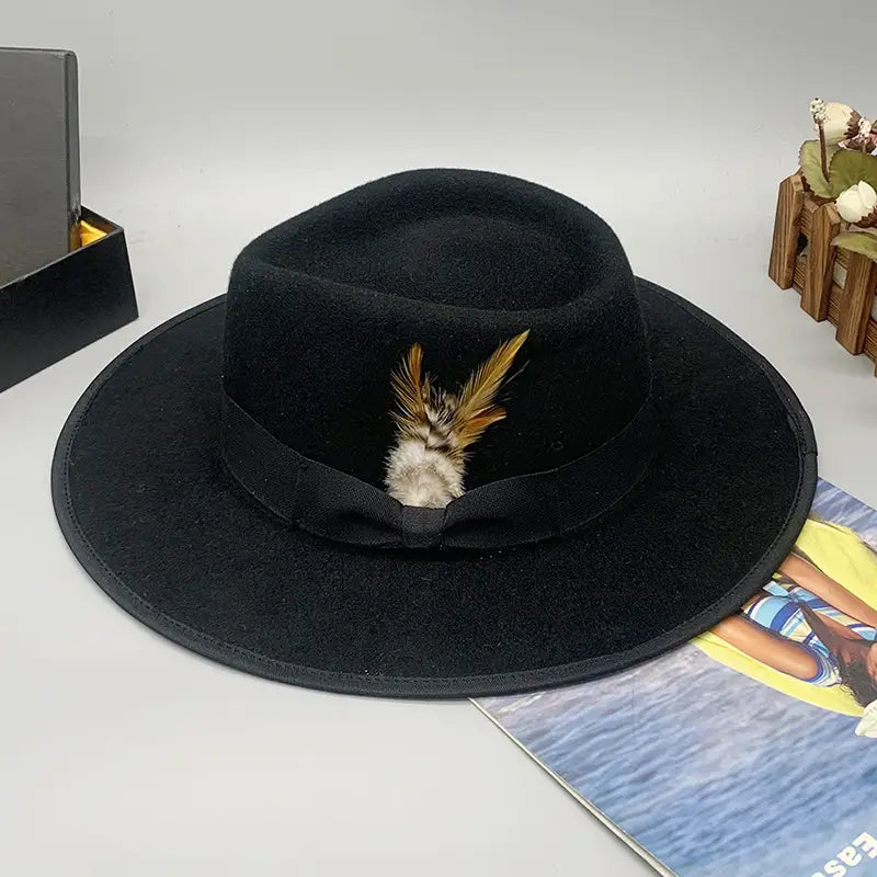 Black woolen felt fedora hat with a matching ribbon band and decorative feather accent suitable for unisex wear.