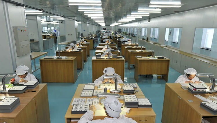 Blouse blanche portée par des ouvriers d’usine, montrant la montre à quartz à maille noire ultrafine pour hommes dans un environnement professionnel