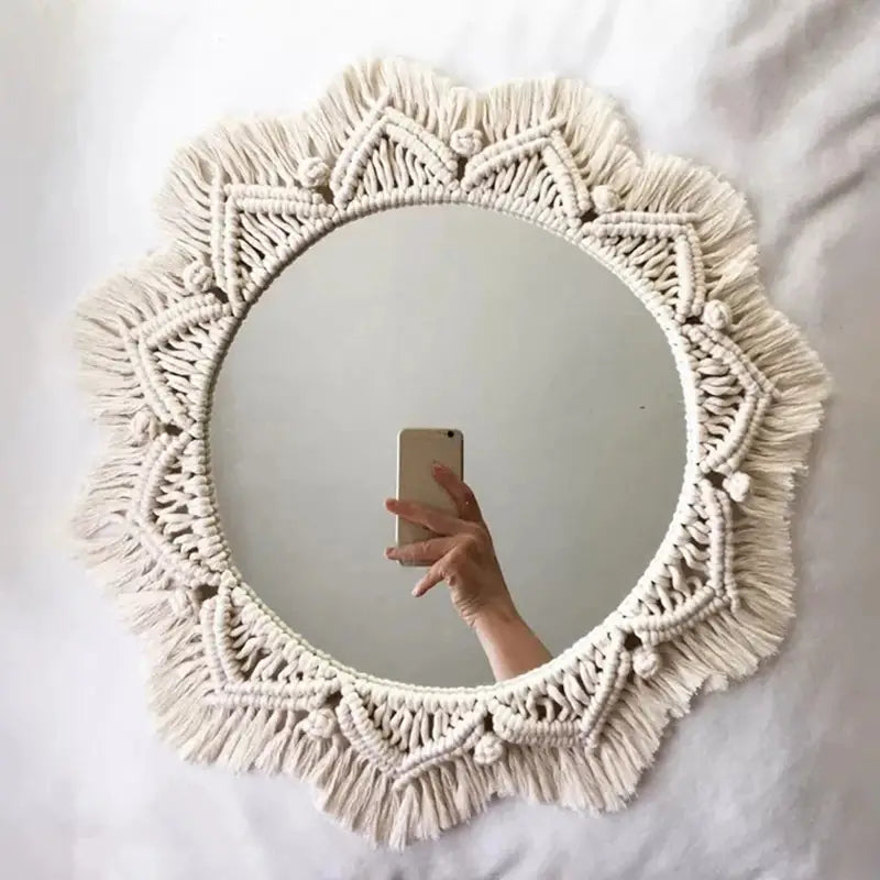Cream-colored macrame wall mirror with intricate geometric patterns and dangling tassels for living room home decor.
