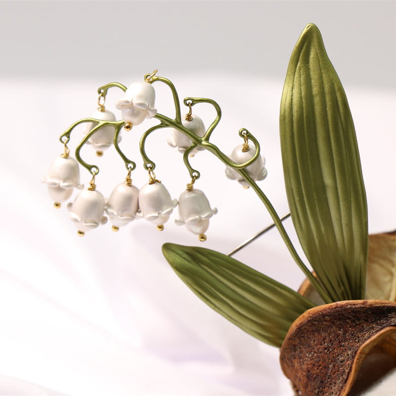 金色調の金属製の茎と葉を備えた、繊細な鈴蘭の真珠のブローチピン。
