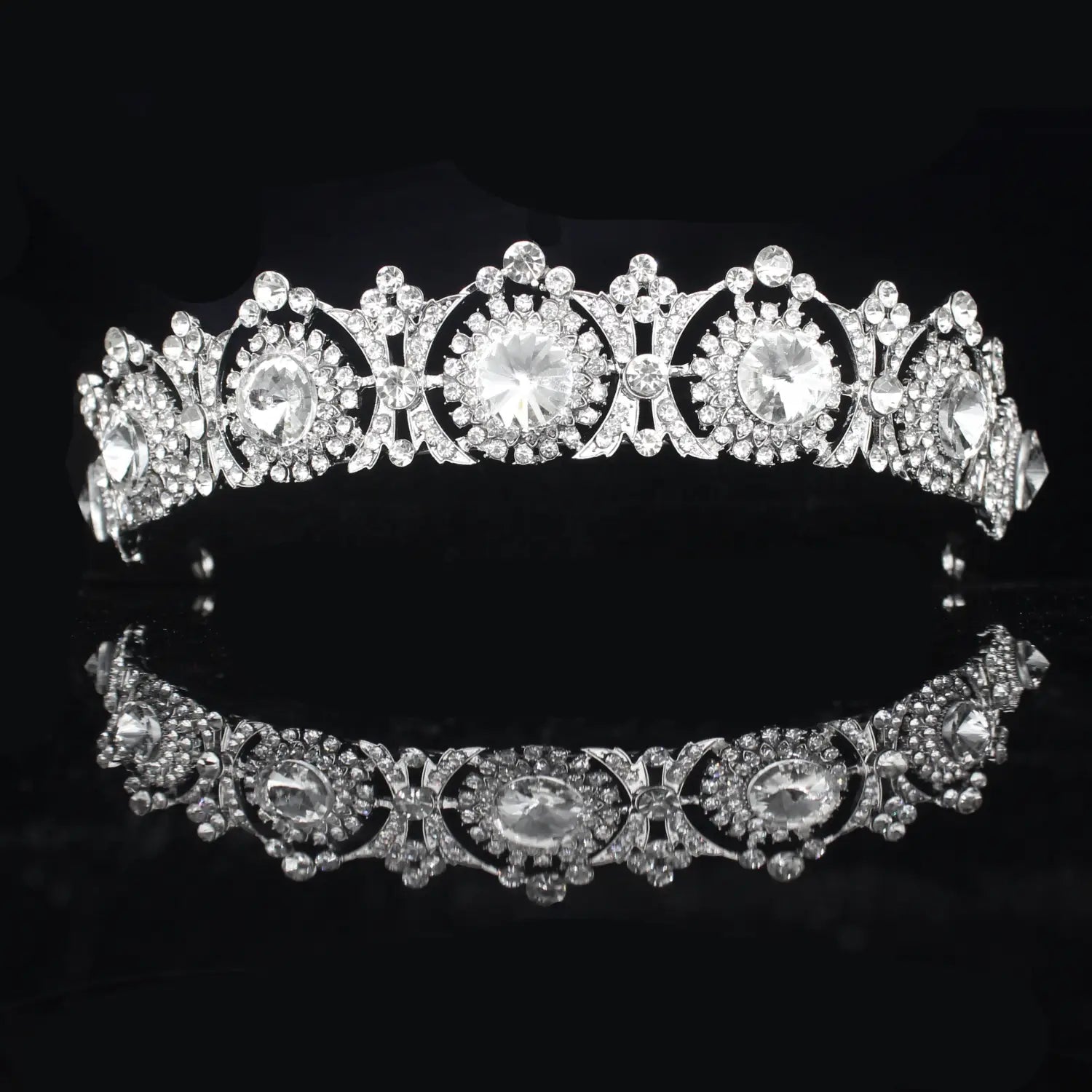 Una diadema de boda floral con tiara de novia de cristal plateado brillante, con filigrana intrincada y múltiples cristales transparentes, con un centro ovalado y patrones ornamentados simétricos.