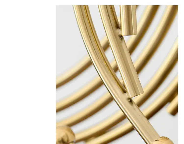 Gold metal abstract sculpture office desk decor featuring a gold-toned metal chandelier with sleek curved rods and spherical accents.