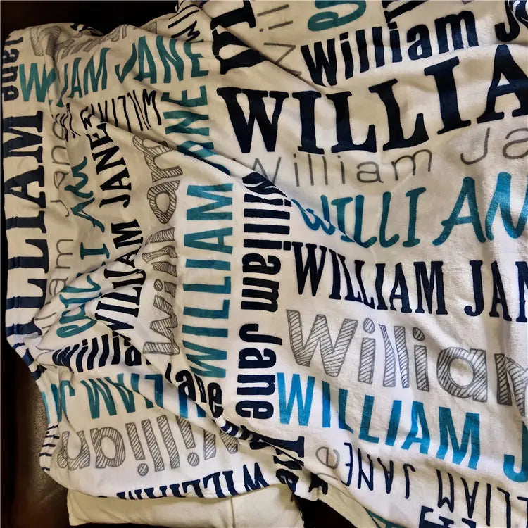Eine weiche, cremefarbene, personalisierte Baby-Wickeldecke aus Fleece mit einem verspielten Muster der Namen william und jane in kräftigen blau-dunkelblauen und grauen Schriftarten