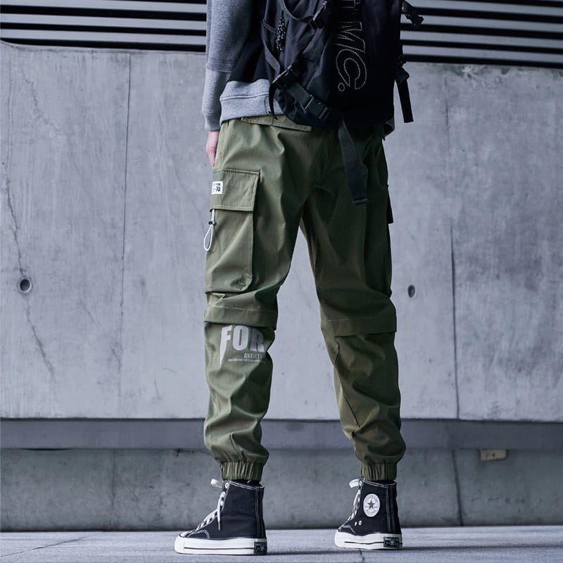 Herren schwarze taktische Cargo-Jogginghosen in Olivgrün mit mehreren Taschen und einem weißen Grafikdruck am Bein, entworfen für den Streetwear-Einsatz.