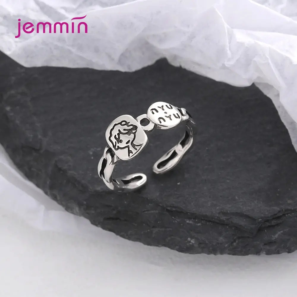 Bague ouverte en argent avec deux breloques gravées, présentant un visage de style dessin animé et une écriture hébraïque, conçus par Jemmin dans une bague réglable à motif facial en argent sterling.