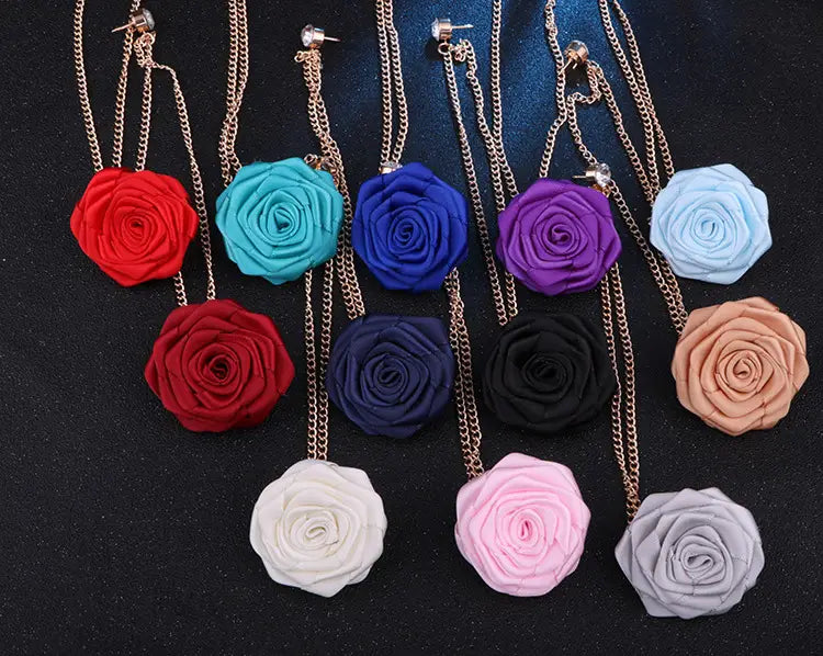 A collection of rose flower brooch tassel chain men suit pins featuring colorful fabric rose pendants in red teal blue purple black pink and white on delicate gold-toned chains.