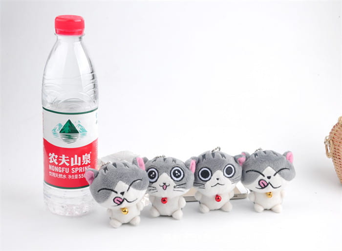 a row of four gray and white plush cat keychains featuring distinct facial expressions and small red or gold bells around their necks, designed as cute gray kitten bag charm toys.