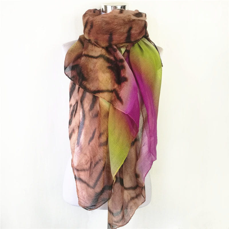 Una bufanda-capa de visón con flecos de leopardo, translúcida, con un degradado de tonos marrón, verde y morado, que presenta patrones de rayas de tigre negras y audaces.