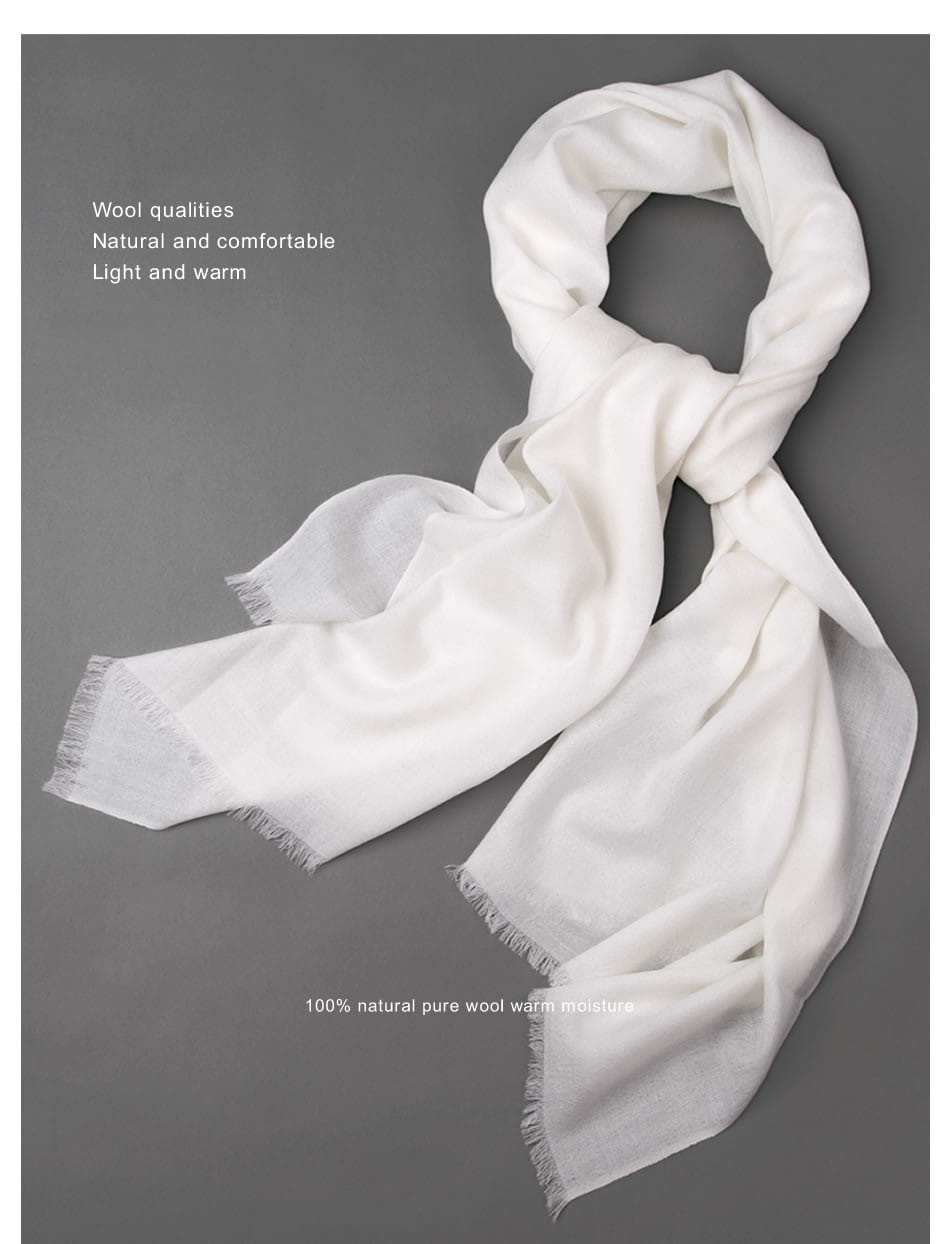 Una bufanda de lana de lujo para mujer en blanco suave, con flecos y una textura ligera y cálida.