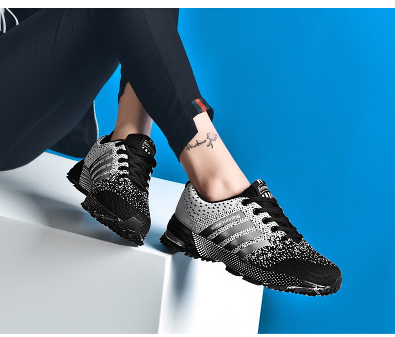 Chaussures de running pour hommes Covadis en maille respirante en noir et en maille chinée gris, avec trois bandes noires audacieuses sur le côté.