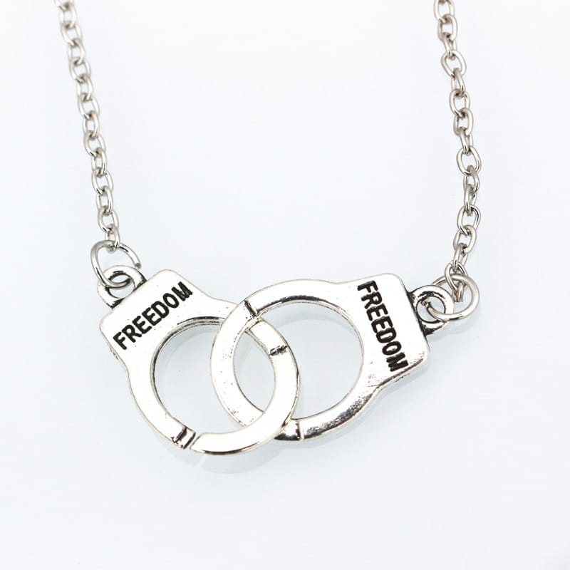 Silver handcuff-shaped necklace in polished silver with freedom engraved on each pad, a stylish fashion jewelry necklace.
