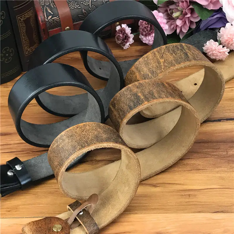 A collection of genuine leather men jeans belts featuring a brass owl belt buckle with matte black and aged tan distressed finishes.