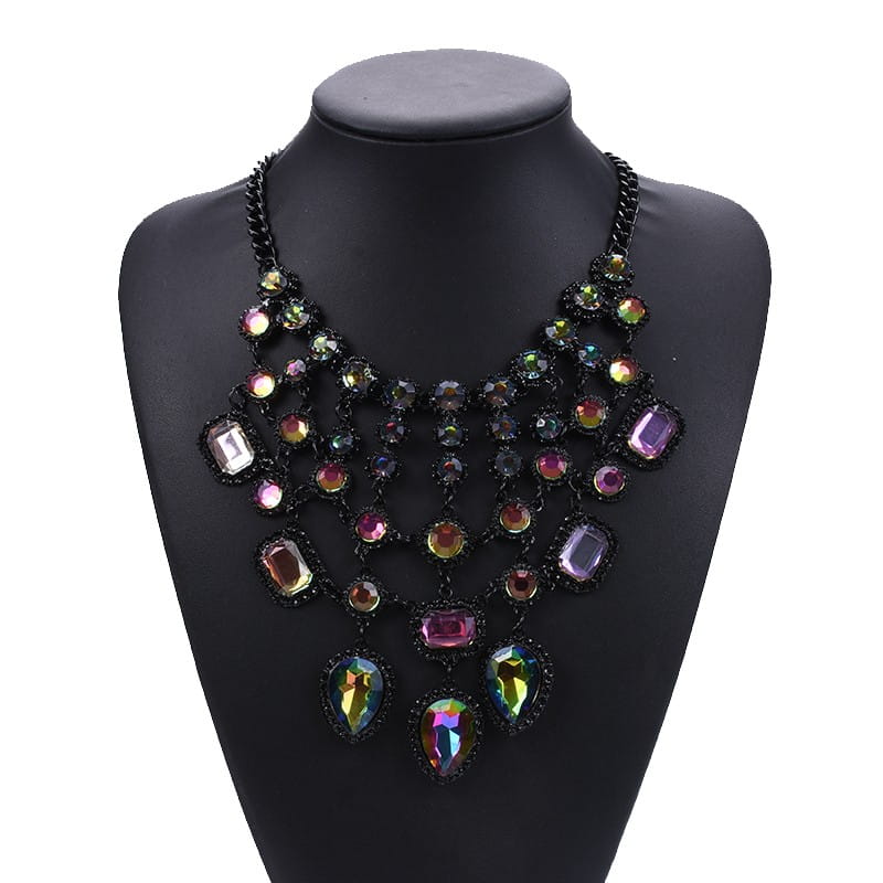 Un collier ras-du-cou noir audacieux, doté de couches superposées de pierres précieuses multicolores irisées, dans diverses coupes, comme accessoire bohème d’affirmation en cristal.