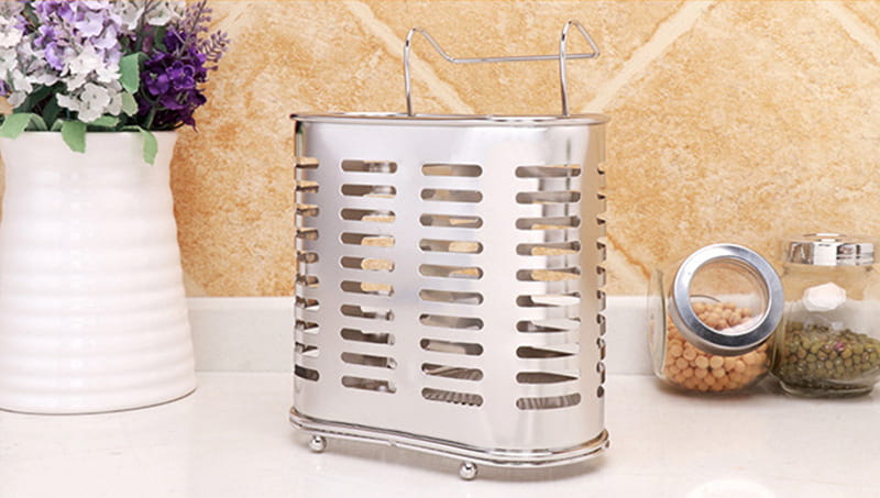 Stainless steel vegetable strainer with handle and small wheels featured on a stainless steel cutlery and utensil storage rack.