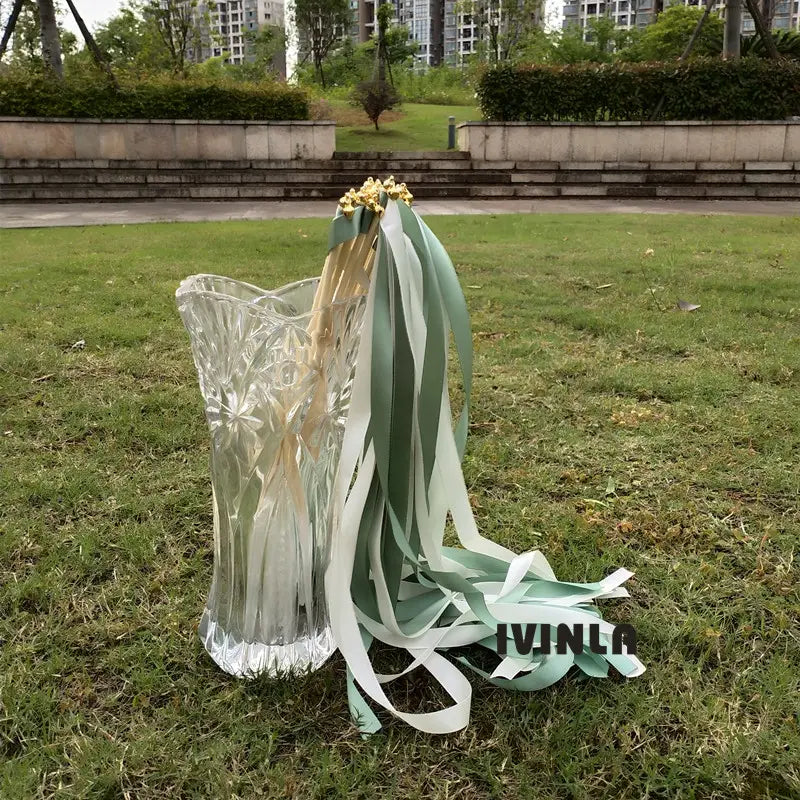 un vase en cristal transparent à découpes complexes, avec un design cannelé et un bord festonné, présenté avec des baguettes ruban de mariage vertes et blanches, lot de 50.