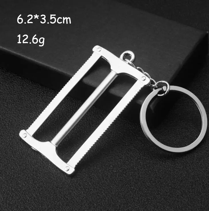 Silver-colored metal mini tool keychain shaped like a miniature saw with serrated edges and a circular ring attached by a chain, part of a multi-tool key ring set.