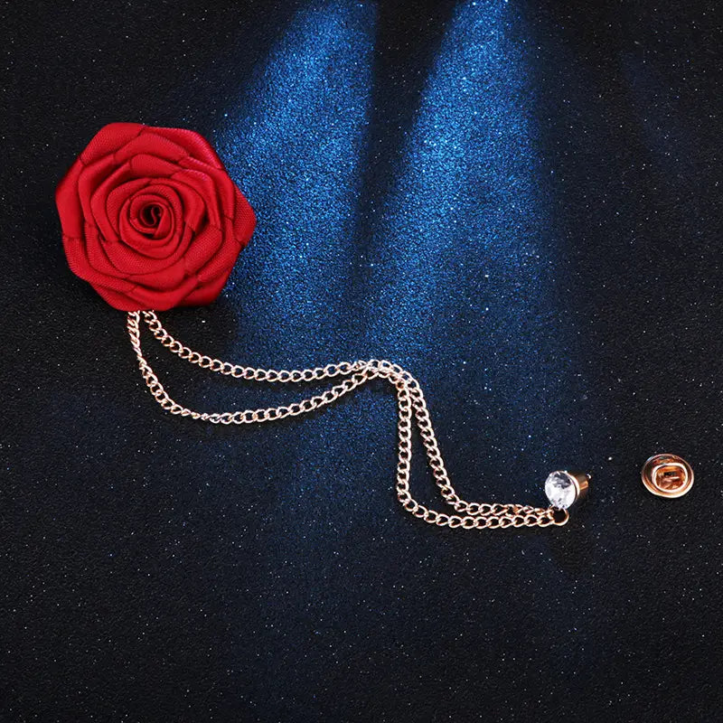 A vibrant red fabric rose pin rose flower brooch features a delicate gold tassel chain and clear crystal accent designed for men suit pin.