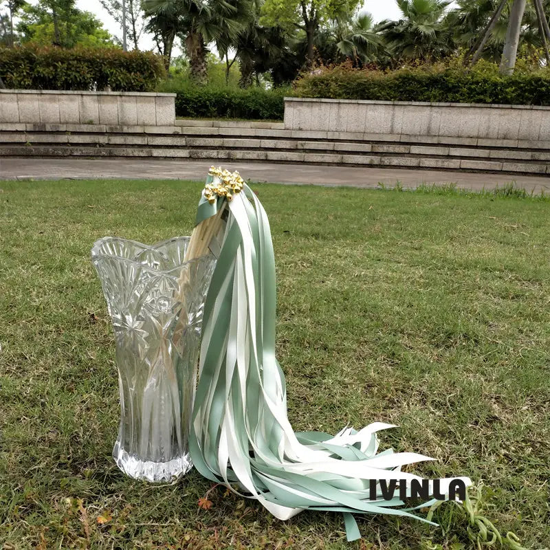un vase en cristal transparent à découpes complexes, avec un design cannelé et un bord festonné, présenté avec des baguettes ruban de mariage vertes et blanches, lot de 50.