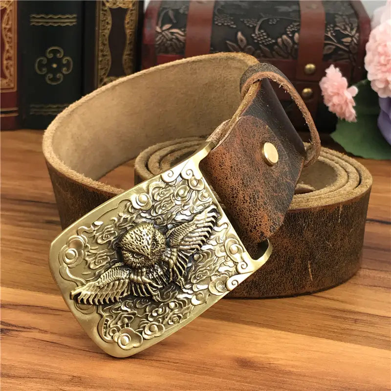 A detailed brass owl belt buckle with intricately carved swirling cloud patterns paired with a rich brown genuine leather strap for men jeans belt.