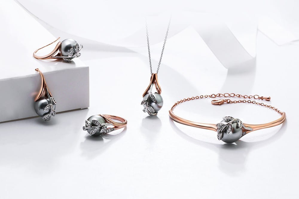 Elegant rose gold black and white crystal statement flower ring featuring dark gray pearls accented with sparkling diamonds and leaf motifs.