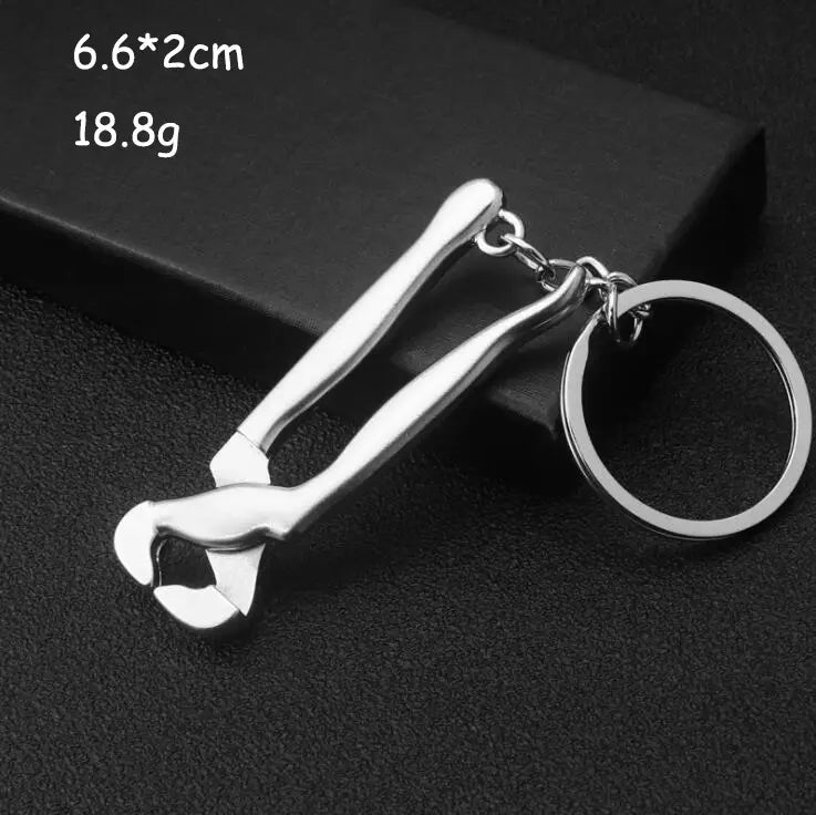 Silver metal mini tool keychain shaped like a miniature bottle opener with a sleek polished finish and attached circular ring for use as a multi-tool key ring.