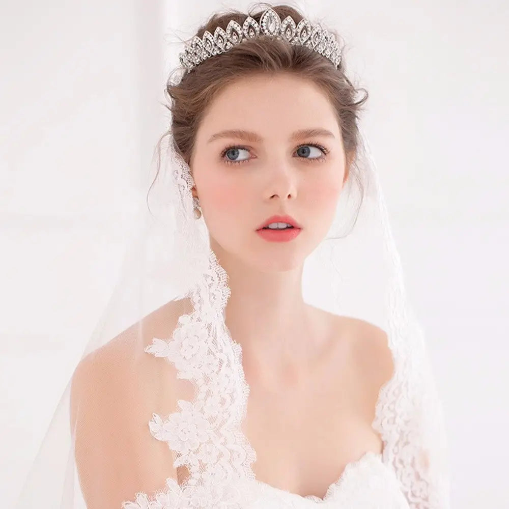 Una diadema de boda floral con tiara de novia de cristal plateado brillante, con ornamentaciones tipo diamante intrincadas y un diseño delicado y elaborado.