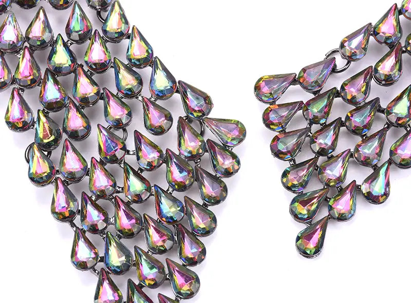 Collier d’affirmation en cristal, ras-du-cou bohème multicolore, featuring des perles irisées en forme de gouttes, disposées dans un design de chaîne en cascade, avec une finition métallisée sombre et des reflets arc-en-ciel étincelants.