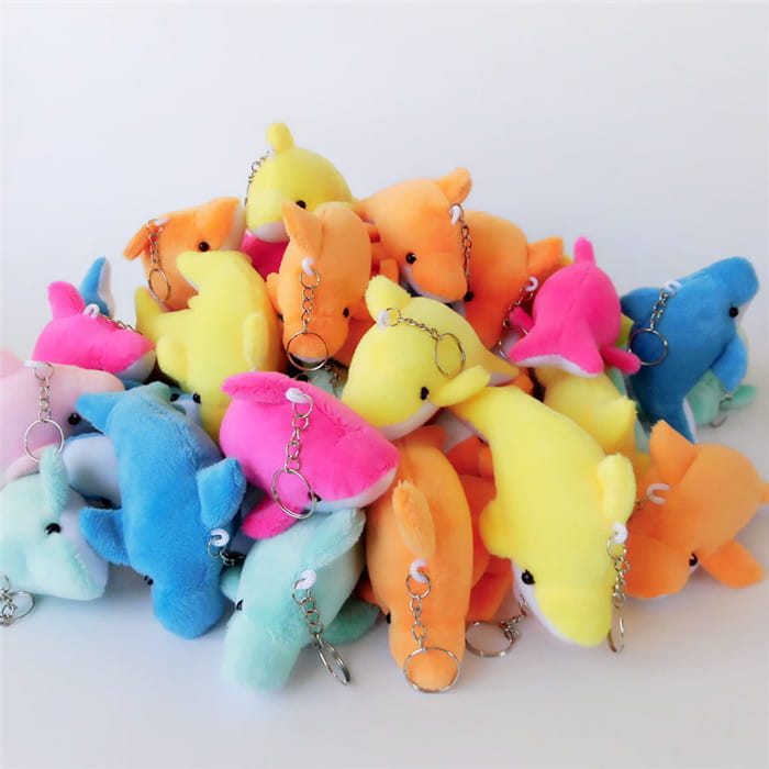 A pile of colorful plush dolphin keychains in vibrant yellow pink orange and blue displayed alongside a plush cat keychain cute gray kitten bag charm toy.