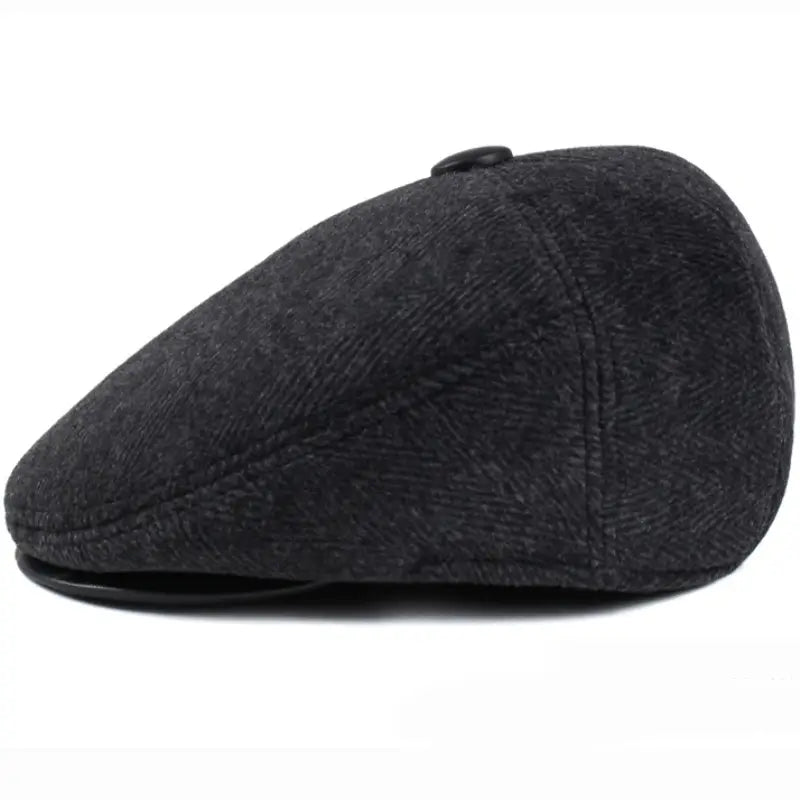 Gorra plana tipo herringbone para hombre en tweed gris oscuro con botón negro en la parte superior, diseñada para uso de invierno con cubreorejas
