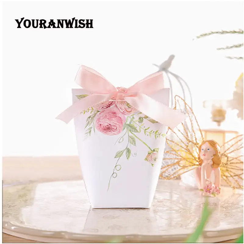 Boîte cadeau en papier blanc présentant des illustrations de rose rose et de feuille verte, attachée avec un nœud en ruban de satin rose pour un lot de boîtes de faveur de mariage en papier floral rose de 50.