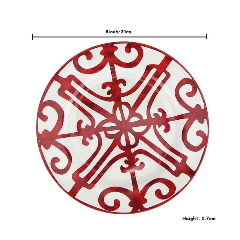 A white bone china ceramic plate with a bold red ornate filigree pattern from the Bone China Red Scroll Dinnerware Set.