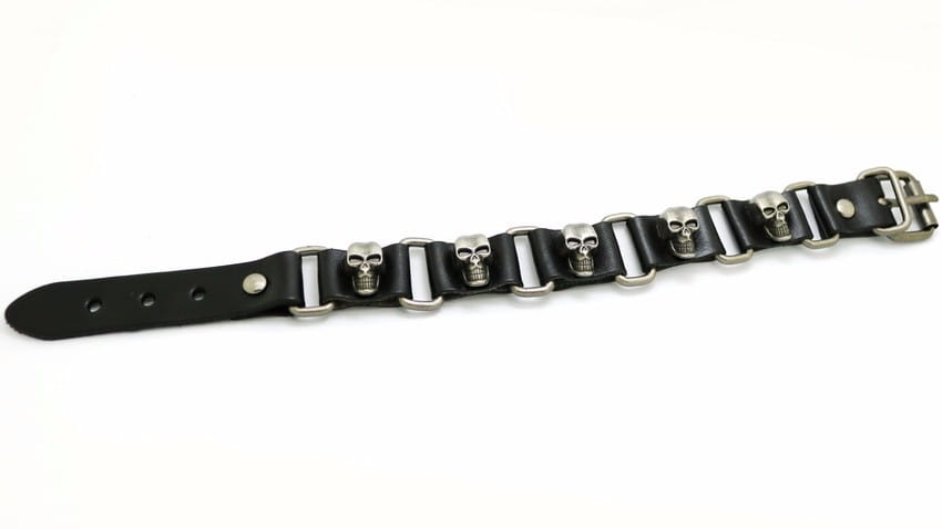 メタルスタッズを備えた、シルバートーンのメタルスカルとバックルのブラックレザーパンクブレスレット。