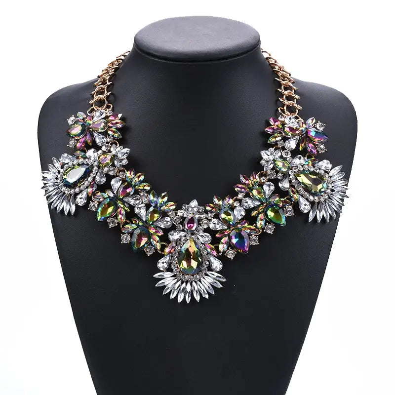 Un collier d’affirmation bohème multicolore éblouissant, avec des motifs floraux complexes et des cristaux irisés et transparents montés sur une chaîne à tons dorés.