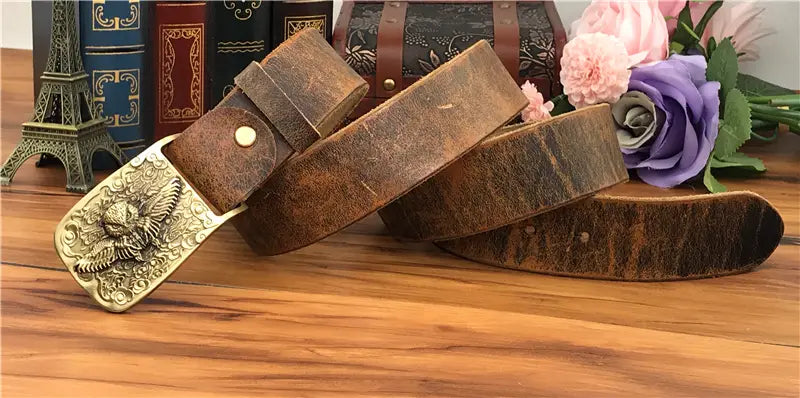 A vintage-style brown genuine leather men jeans belt featuring a detailed brass buckle with an ornate dragon design.