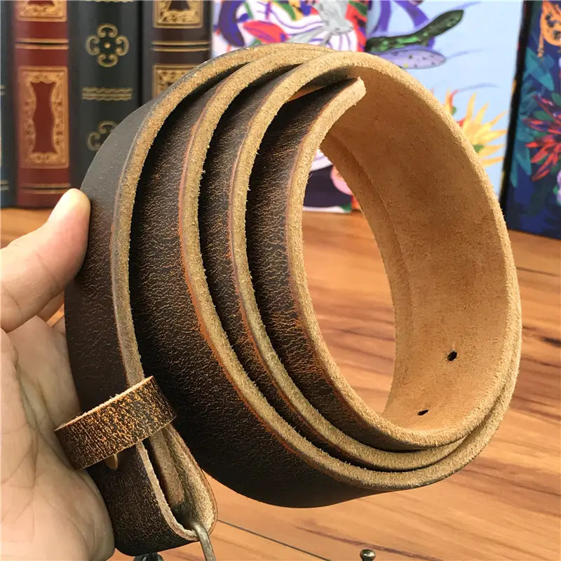 A coiled dark brown genuine leather men jeans belt with tan inner lining and a simple brass owl belt buckle.