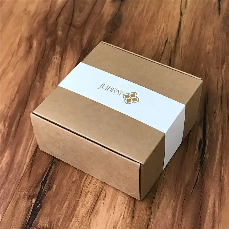 a brown kraft paper box with a white label featuring the jubray brand name and logo for a brass owl belt buckle made of genuine leather designed for men jeans belts