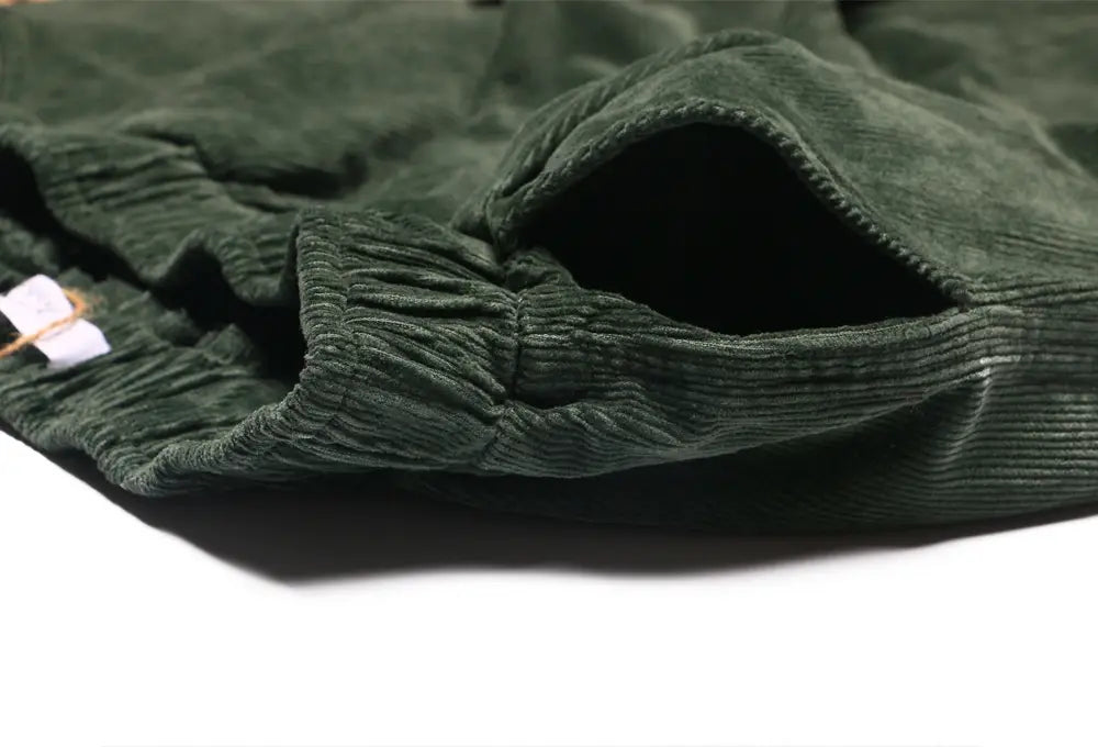 pantalones de pana de pierna ancha verde oscuro con cintura elástica, cinturilla acanalada y cordón para un ajuste holgado y una longitud de pantalón ajustable, mostrados en imágenes detalladas.