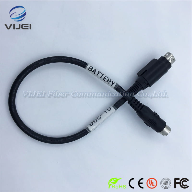 Black coiled battery charger cable with metallic connectors and white labeling reading battery and dco-10 adapted for optical fiber fusion use with Fujikura fusion splicer.