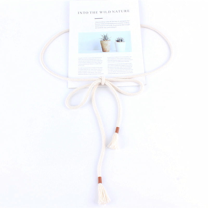 Cream-colored macrame cord braided rope belt with tassels and brown leather accents for women as a tassel waistband dress accessory.