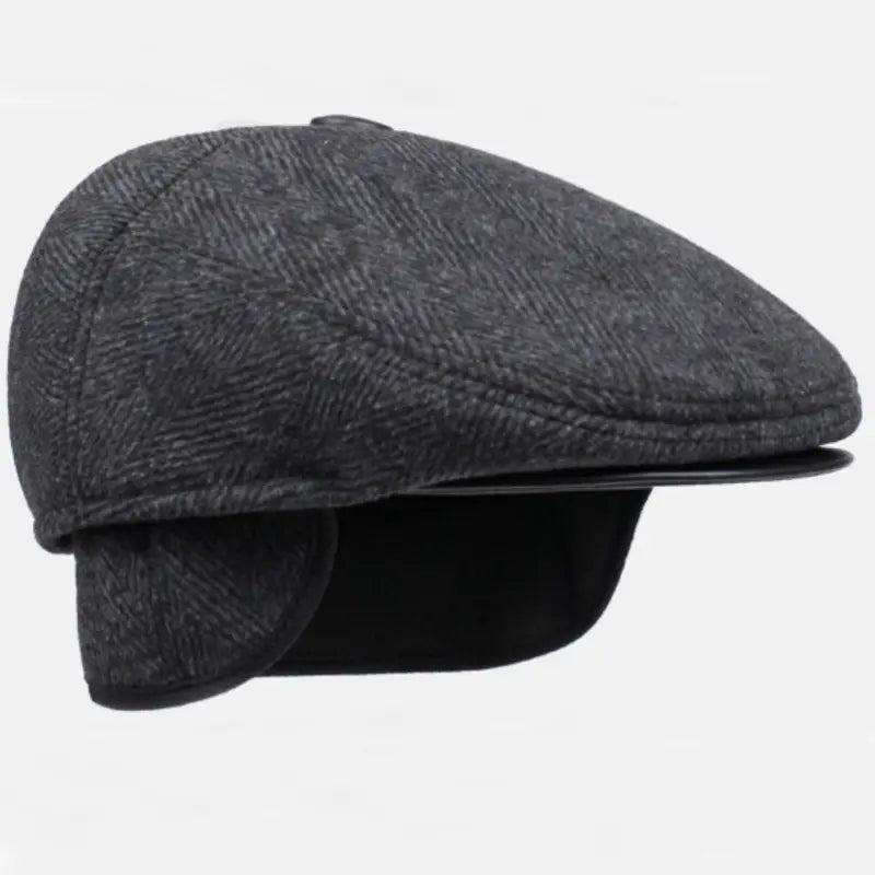 Boina de invierno para hombre tipo herringbone en gris oscuro con patrón herringbone, con visera de cuero negra y cubreorejas.