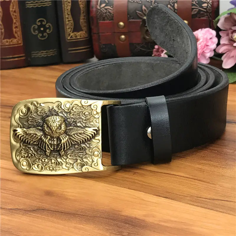 Black leather men jeans belt with a brass owl detailed gold-toned rectangular buckle and intricate carved design.